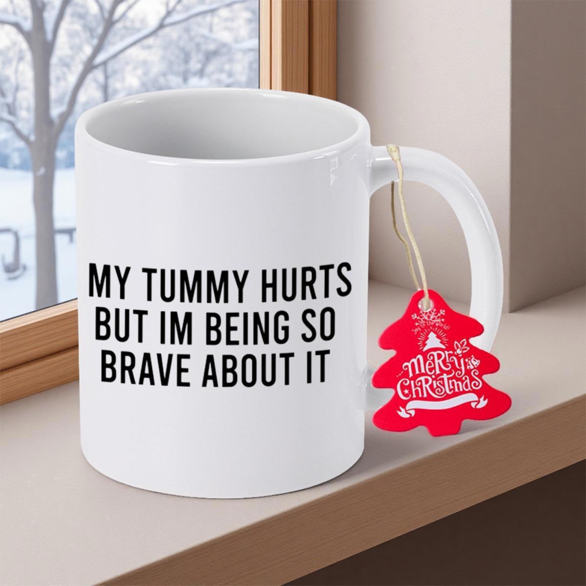 Tailorly White Ceramic 11 oz Mug - My Tummy Hurts But Im Being So Brave About It Resting On Wooden Window Sill With Red Tag Mug