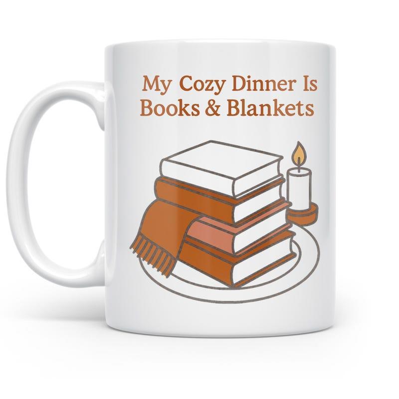 Tailorly White Ceramic 11 oz Mug - My Cozy Dinner Is Books Blankets Stacked Vintage Volumes With A Glowing Candle And Cozy Blanket Books