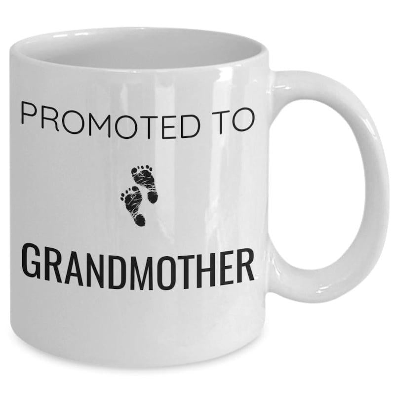 Tailorly White Ceramic 11 oz Mug - Promoted To Grandmother Tiny Black Infant Feet Marks Centered Among Bold Typography Footprints
