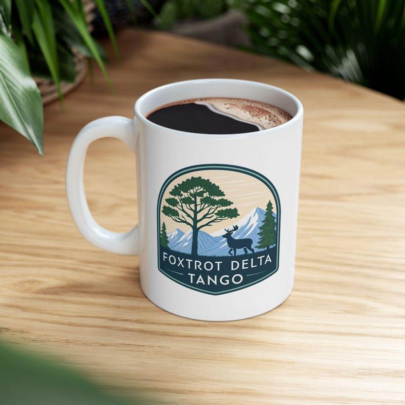 Tailorly White Ceramic 11 oz Mug - Foxtrot Delta Tango Scenic Nature Badge With Pine Tree And Mountain Peaks Under Daylight Deer