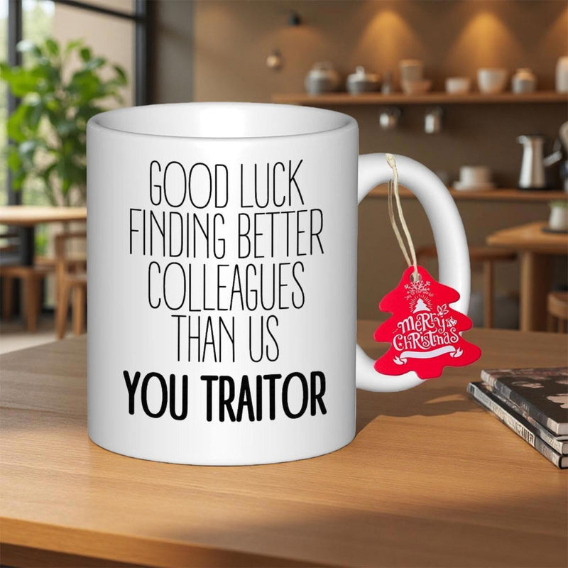 Tailorly White Ceramic 11 oz Mug - Good Luck Finding Better Colleagues Than Us You Traitor Sleek Standing On Wooden Table With Red Tag Mug