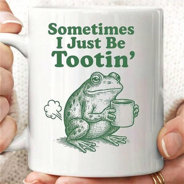 Tailorly White Ceramic 11 oz Mug - Sometimes I Just Be Tootin' Green Sketch Style Holding Small Mug Releasing A Puffy Cloud Frog