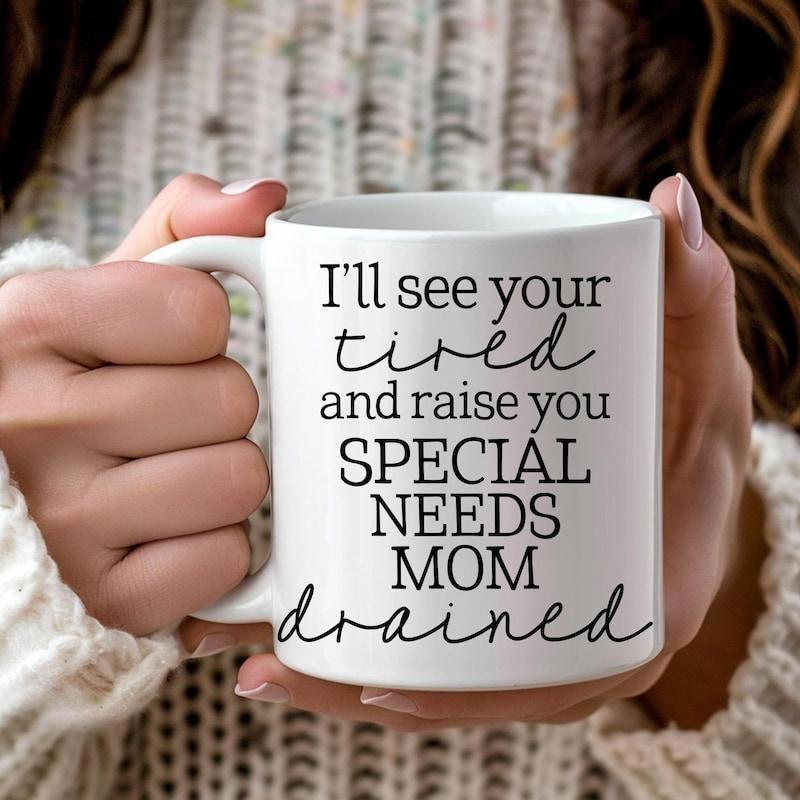 Tailorly White Ceramic 11 oz Mug - Ill See Your Tired And Raise You Special Needs Mom Drained Minimalist White Ceramic Vessel Held By Gentle Hands In Cozy Sweater