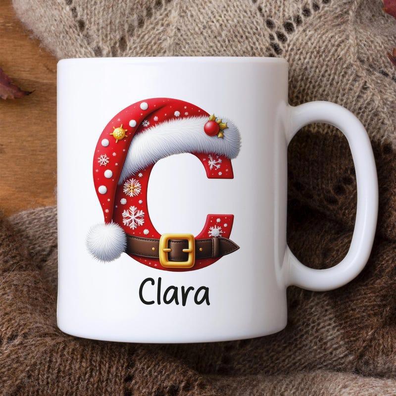 Tailorly White Ceramic 11 oz Mug - Clara Festive Red Letter With Santa Hat And Gold Buckle Initial