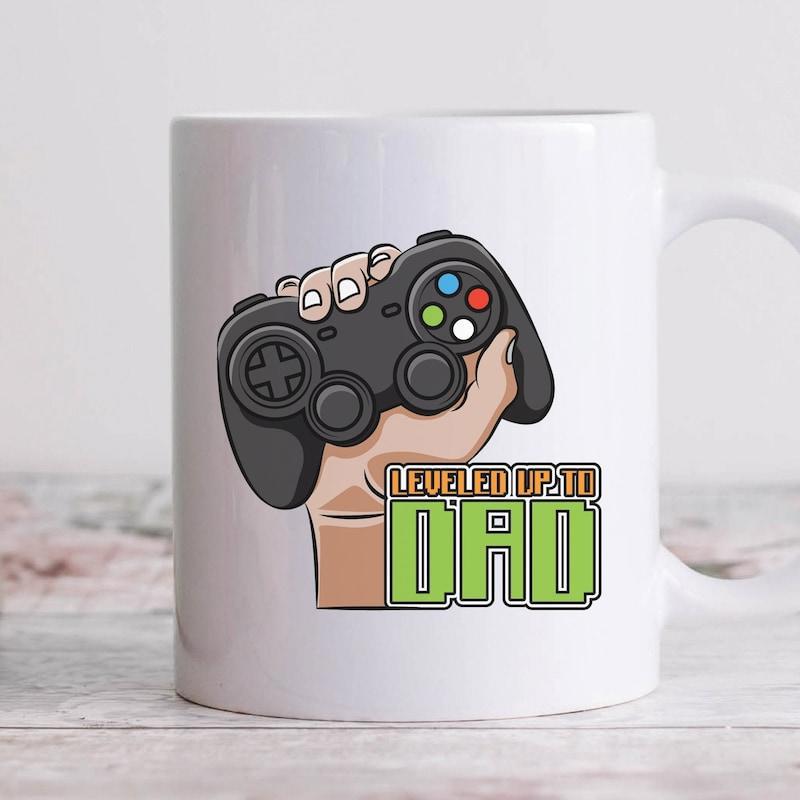 Tailorly White Ceramic 11 oz Mug - Level Up Dad Cartoon Hand Gripping A Black Video Game Controller With Vibrant Buttons Controller