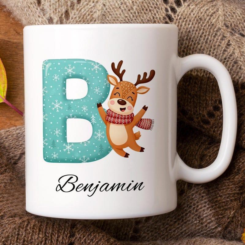 Tailorly White Ceramic 11 oz Mug - Benjamin Festive Teal Letter With Snowflakes Beside A Joyful Cartoon Winter Reindeer