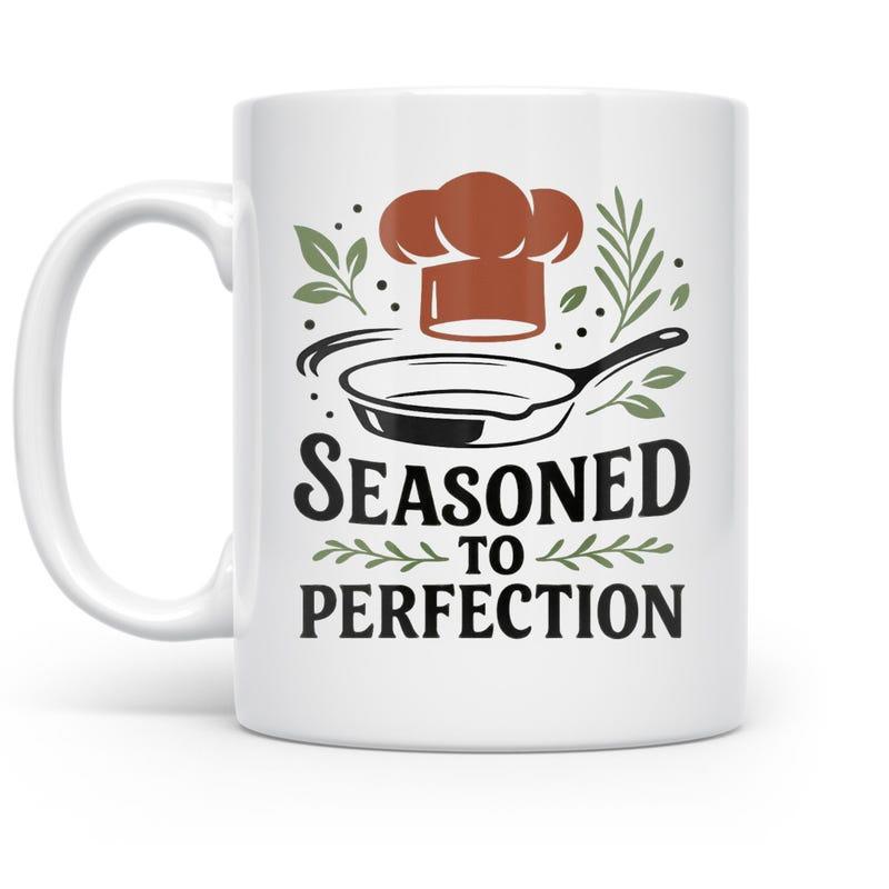 Tailorly White Ceramic 11 oz Mug - Seasoned To Perfection Chef Hat Floating Above A Skillet Surrounded By Fresh Kitchen Herb Sprigs Pan