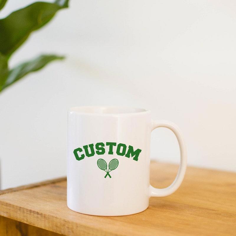 Tailorly White Ceramic 11 oz Mug - Custom Classic Green Minimalist Athletic Design Featuring Two Small Crossed Sports Style Racket