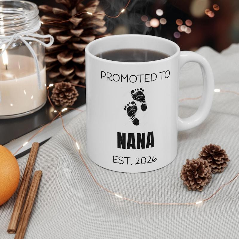 Tailorly White Ceramic 11 oz Mug - Promoted To Nana Est 2026 Tiny Darling Infant Feet Walking Across A Minimalist Clean Background Footprint