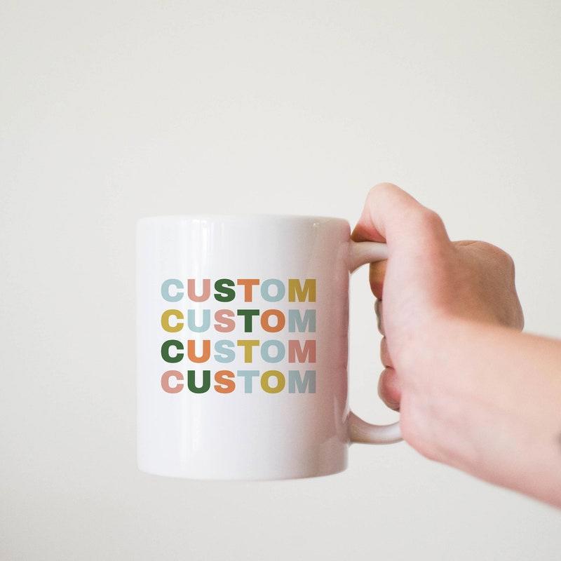 Tailorly White Ceramic 11 oz Mug - Custom Clean With Colorful Repeating Letters Being Held By Hand Mug