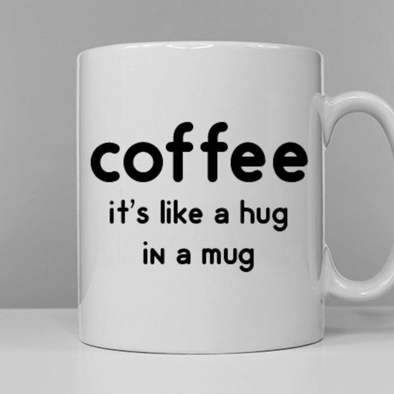Tailorly White Ceramic 11 oz Mug - Coffee It's Like A Hug In A Mug Simple Ceramic Vessel Standing On White Surface Under Soft Neutral Light Mug