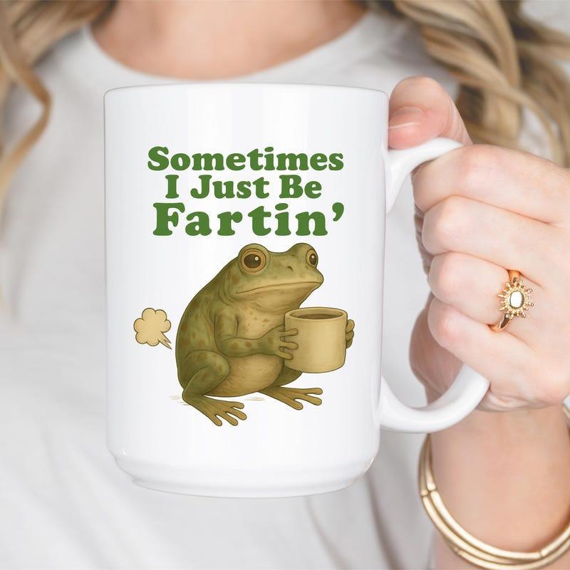 Tailorly White Ceramic 11 oz Mug - Sometimes I Just Be Fartin Green Textured Frog Sitting While Holding A Cup Of Coffee Frog