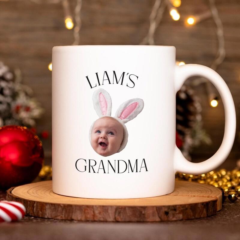 Tailorly White Ceramic 11 oz Mug - Liam's Grandma Smiling Baby Face Wearing Cute Pink And White Bunny Ears Mug