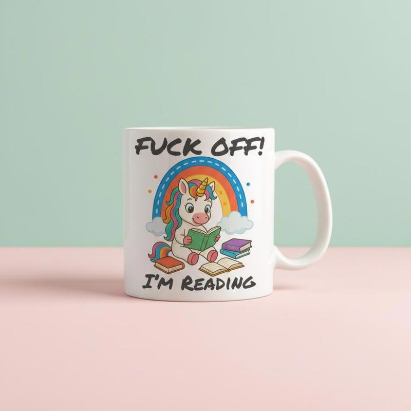 Tailorly White Ceramic 11 oz Mug - Fuck Off Im Reading Adorable Cartoon Creature Sitting Beneath Rainbow And Piles Of Books Unicorn