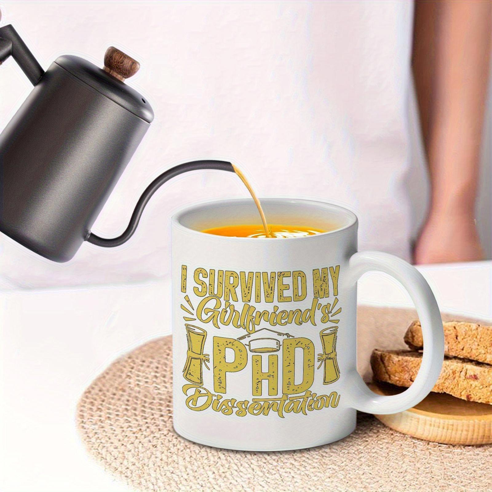 Tailorly White Ceramic 11 oz Mug - I Survived My Girlfriends Phd Dissertation White Ceramic Material With Golden Textured Lettering And Academic Graduation Symbols