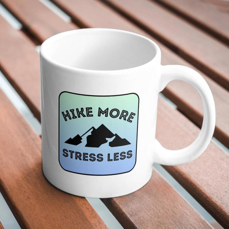 Tailorly White Ceramic 11 oz Mug - Hike More Stress Less Silhouette Of Jagged Black Peaks Under A Soft Green Blue Gradient Mountains
