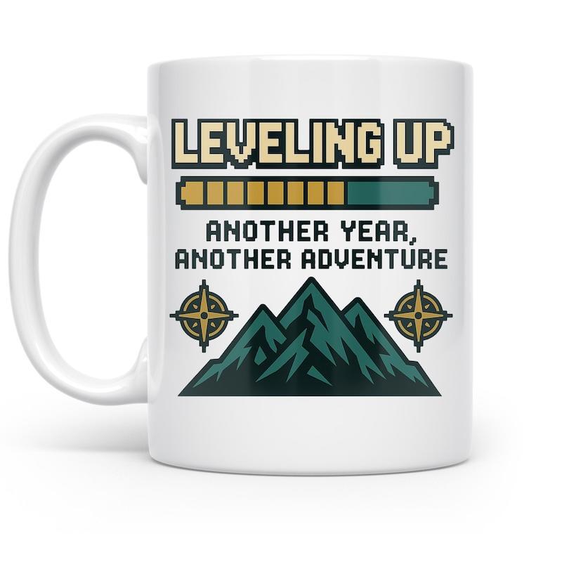 Tailorly White Ceramic 11 oz Mug - Leveling Up Another Year Another Adventure Pixelated Loading Bar Floating Over Jagged High Wilderness Peaks With Compass Icons
