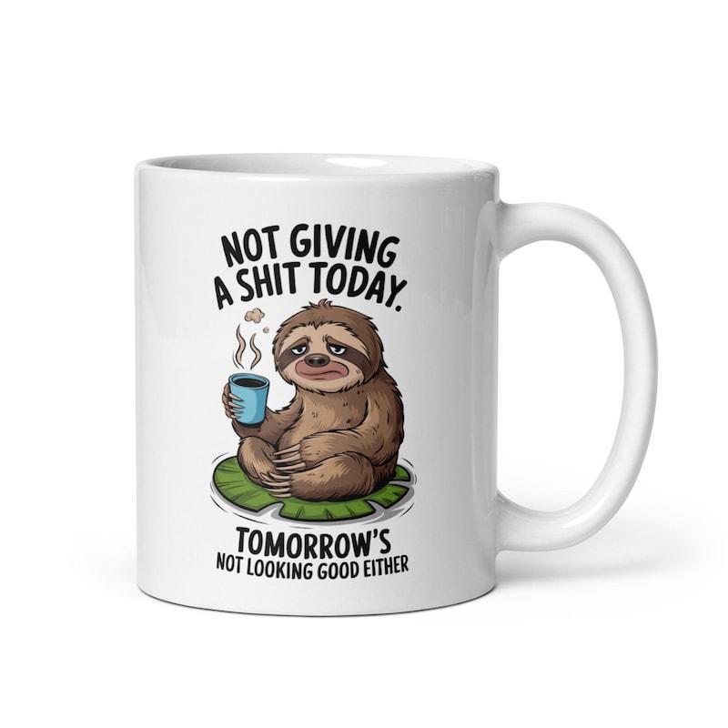 Tailorly White Ceramic 11 oz Mug - Not Giving A Shit Today Tomorrows Not Looking Good Either Relaxed Brown Animal Holding Hot Coffee Sitting On Green Leaf Sloth