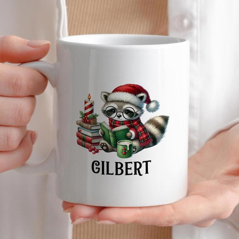 Tailorly White Ceramic 11 oz Mug - Gilbert Festive Raccoon Wearing Red Hat Reading Book Beside Stacked Books Raccoon