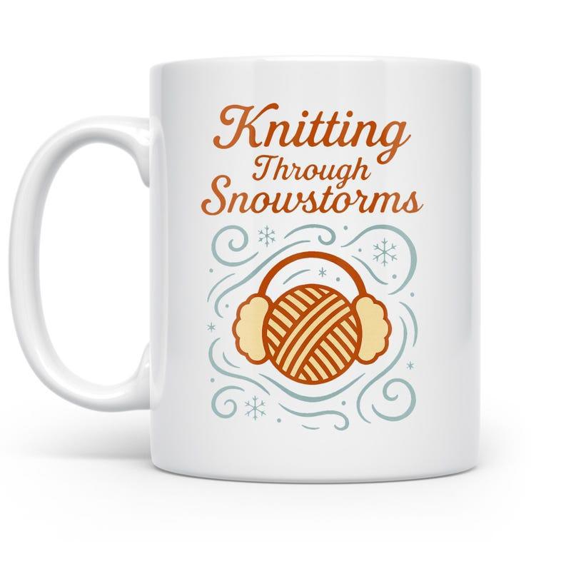 Tailorly White Ceramic 11 oz Mug - Knitting Through Snowstorms Stylized Yarn Ball Wearing Fuzzy Earmuffs Among Swirling Winter Wind Snowflakes Yarn Ball