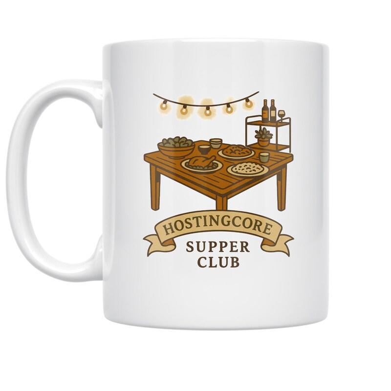 Tailorly White Ceramic 11 oz Mug - Hostingcore Supper Club Cozy Wooden Dining Setting With Warm Festive String Lights Above Table
