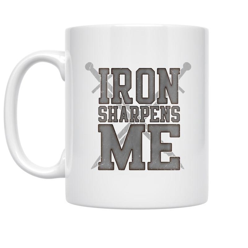 Tailorly White Ceramic 11 oz Mug - Iron Sharpens Me Two Gray Crossed Swords Behind Bold Collegiate Style Text Design Sword