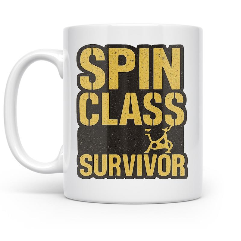 Tailorly White Ceramic 11 oz Mug - Spin Class Survivor Distressed Golden Typography Over Solid Black Rectangular Background Stationary Exercise Bike