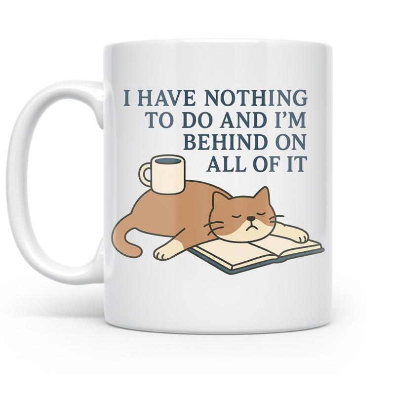 Tailorly White Ceramic 11 oz Mug - I Have Nothing To Do And I'm Behind On All Of It Cartoon Ginger Cat Sleeping On Open Book With Small Coffee Cup Cat