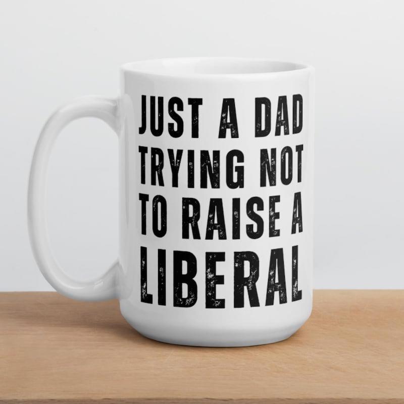 Tailorly White Ceramic 11 oz Mug - Just A Dad Trying Not To Raise A Liberal Distressed Bold Black Block Letters Printed On Smooth Ceramic Surface Mug