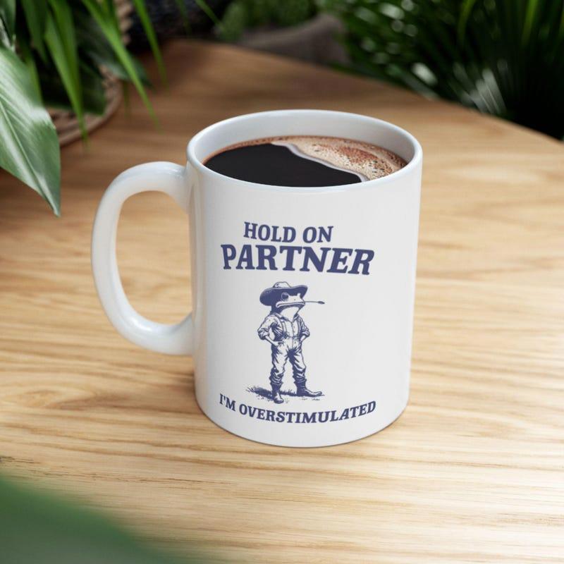 Tailorly White Ceramic 11 oz Mug - Hold On Partner Im Overstimulated Dressed As A Brave Cowboy Standing Confidently Wearing Large Leather Boots Frog