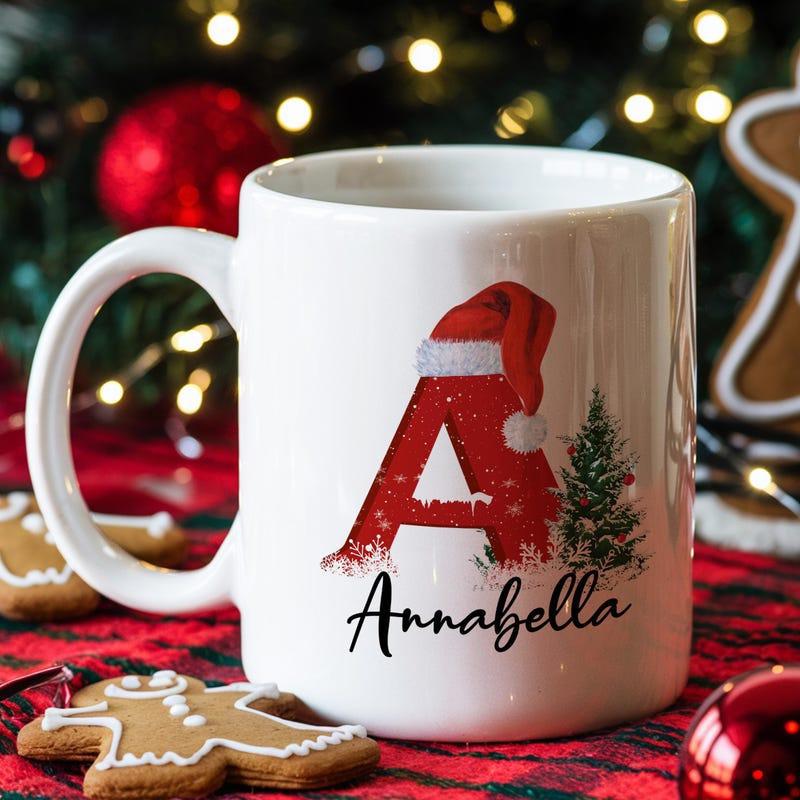 Tailorly White Ceramic 11 oz Mug - Annabella Festive Red Initial Letter Wearing Santa Hat Beside Snowy Pine Mug