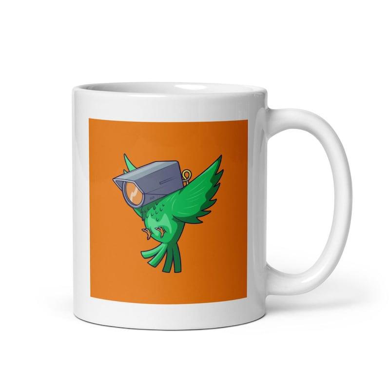 Tailorly White Ceramic 11 oz Mug - Green Mechanical Bird Flying Gracefully Across A Vibrant Orange Square Bird