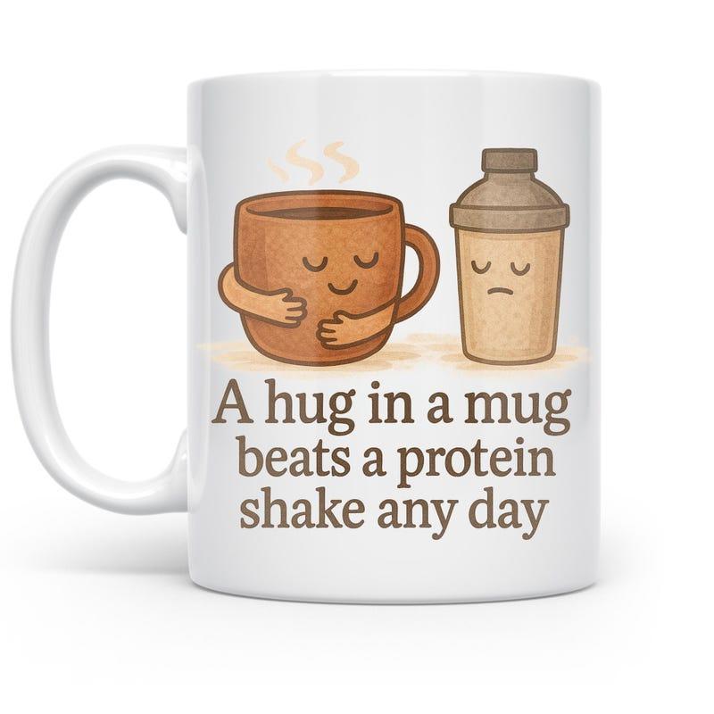 Tailorly White Ceramic 11 oz Mug - A Hug In A Mug Beats A Protein Shake Any Day Cute Personified Steaming Brown Coffee Cup Hugging Itself Beside Shaker Mug