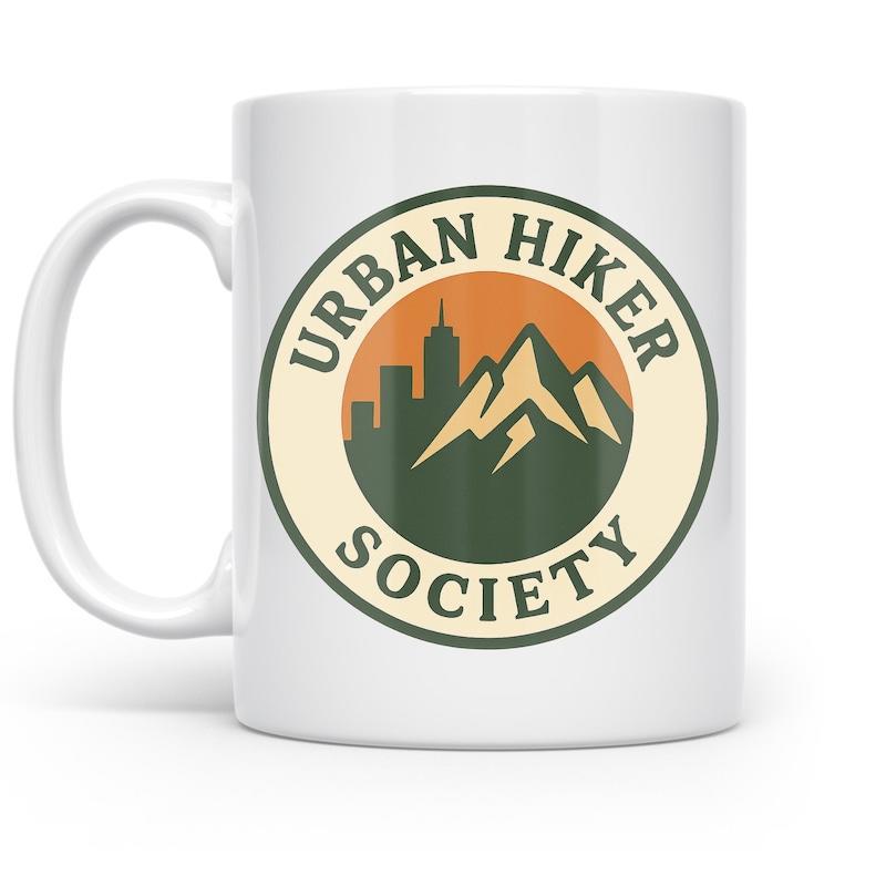 Tailorly White Ceramic 11 oz Mug - Urban Hiker Society Circular Badge Featuring Silhouettes Of Mountain Peaks And Tall City Skyline