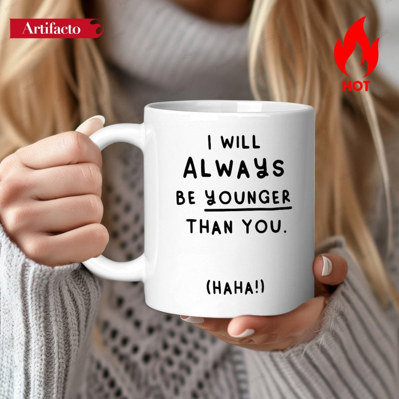 Tailorly White Ceramic 11 oz Mug - I Will Always Be Younger Than You Haha Minimalist White Ceramic Vessel Held By Gentle Hands Against Soft Sweater Mug
