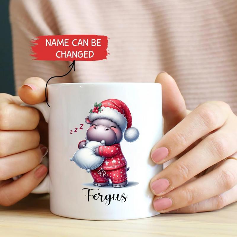 Tailorly White Ceramic 11 oz Mug - Fergus Wearing Red Festive Christmas Pajamas And Santa Hat Holding Soft Pillow Hippo
