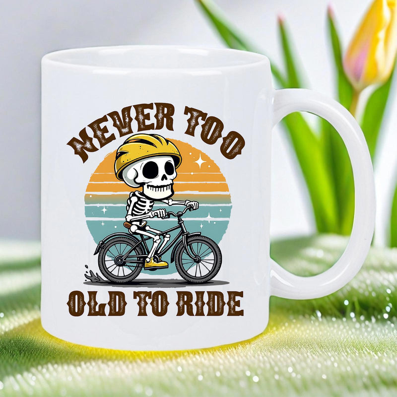 Tailorly White Ceramic 11 oz Mug - Never Too Old To Ride Cartoon Skeleton Wearing Yellow Helmet Riding Bicycle Under Retro Sunset Skeleton