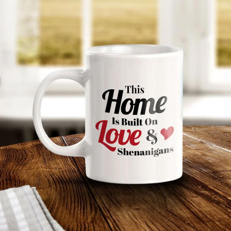 Tailorly White Ceramic 11 oz Mug - This Home Is Built On Love Shenanigans Elegant White Ceramic Piece Resting Upon A Rustic Wooden Surface Mug