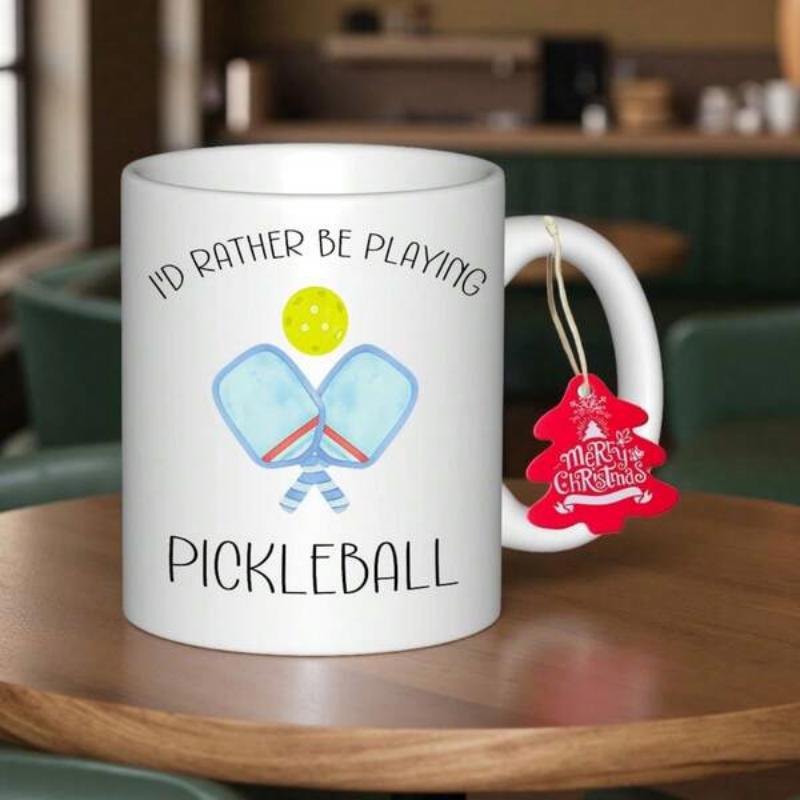 Tailorly White Ceramic 11 oz Mug - Id Rather Be Playing Pickleball Two Crossed Blue Paddles With A Yellow Ball Floating Above Pickleball Paddle