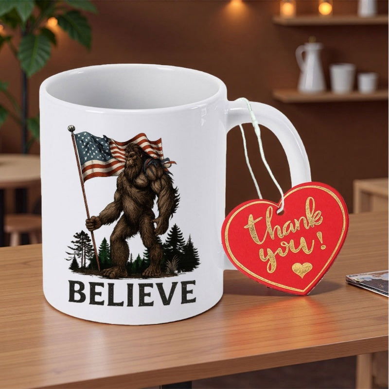 Tailorly White Ceramic 11 oz Mug - Believe Muscular Legendary Bigfoot Holding American Flag Standing Among Pine Trees Forest Sasquatch
