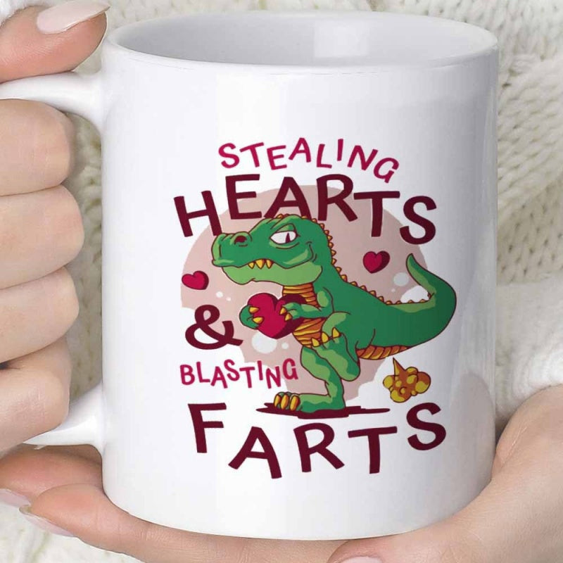 Tailorly White Ceramic 11 oz Mug - Stealing Hearts Blasting Farts Playful Green Cartoon Creature Holding A Red Heart Among Floating Shapes Dinosaur