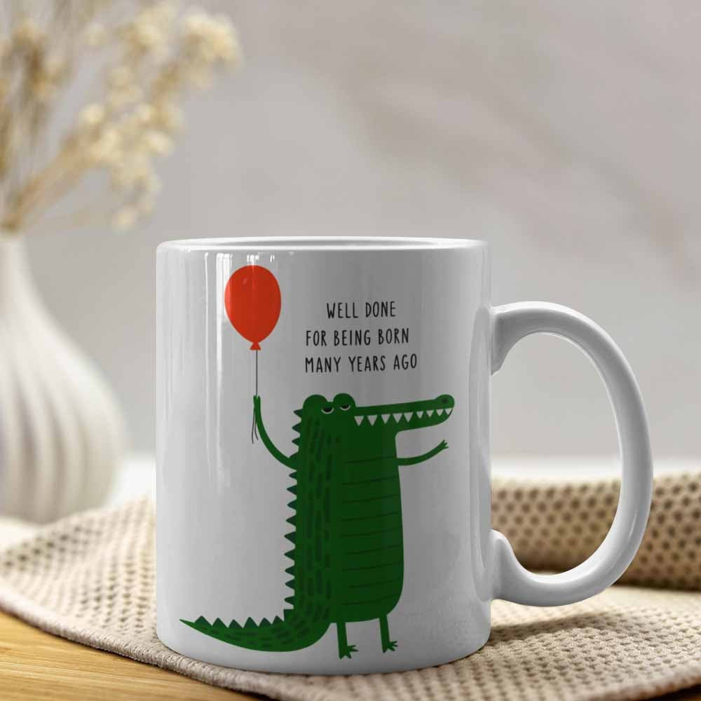 Tailorly White Ceramic 11 oz Mug - Well Done For Being Born Many Years Ago Whimsical Cartoon Alligator Holding A Single Red Balloon In The Air Crocodile