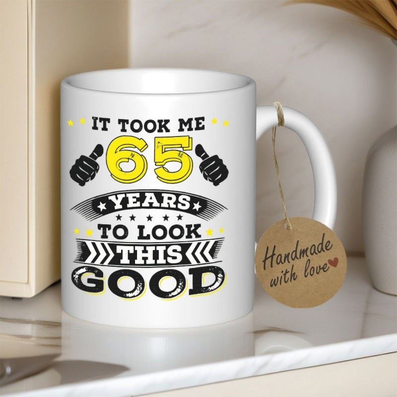 Tailorly White Ceramic 11 oz Mug - It Took Me 65 Years To Look This Good Ceramic Surface Featuring Vibrant Yellow Typography With Decorative Thumbs Up Icons Mug