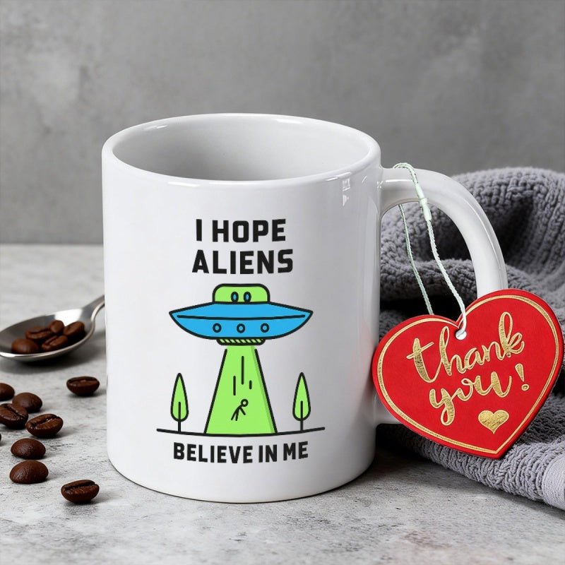 Tailorly White Ceramic 11 oz Mug - I Hope Aliens Believe In Me Stylized Cartoon Flying Saucer Beaming Up Tiny Stick Figure Among Small Trees Spaceship