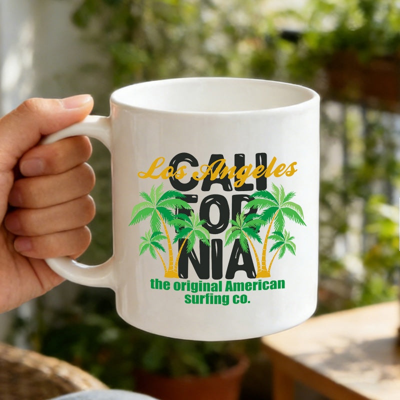 Tailorly White Ceramic 11 oz Mug - Los Angeles California The Original American Surfing Co Vibrant Green Palm Trees Framing Bold Text In A Sunny Garden Setting
