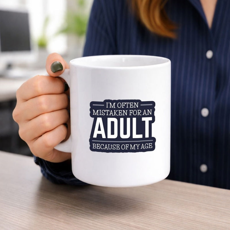 Tailorly White Ceramic 11 oz Mug - Im Often Mistaken For An Adult Because Of My Age Pure With Humorous Typographic Quote Held By Hand Mug