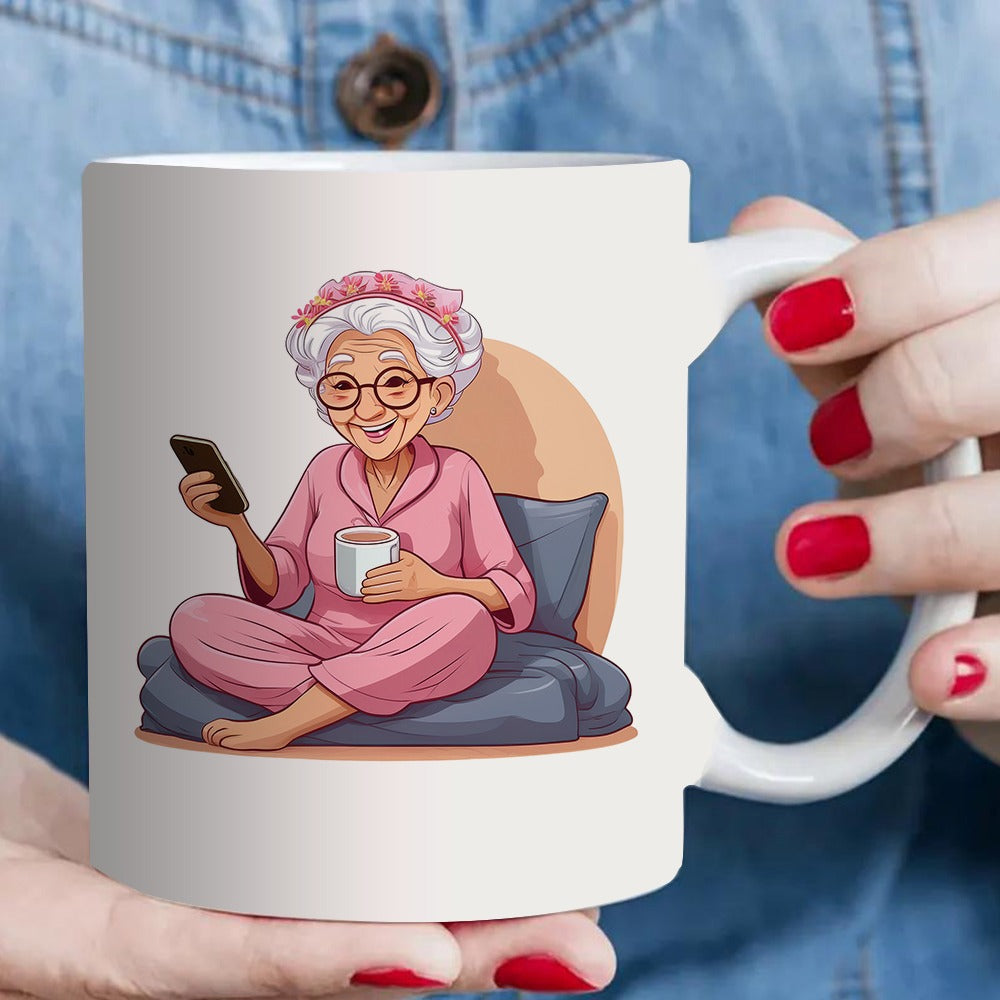Tailorly White Ceramic 11 oz Mug - a single coffee mug designed for an elderly woman who is tea while using her phone dressed in comfortable pink pajamas