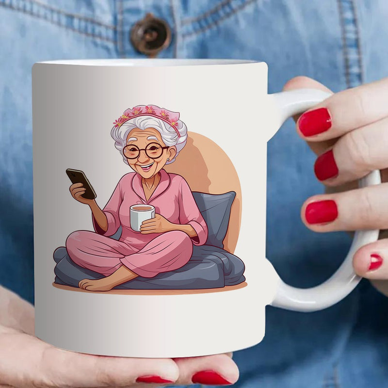 Tailorly White Ceramic 11 oz Mug - a single coffee mug designed for an elderly woman who is tea while using her phone dressed in comfortable pink pajamas
